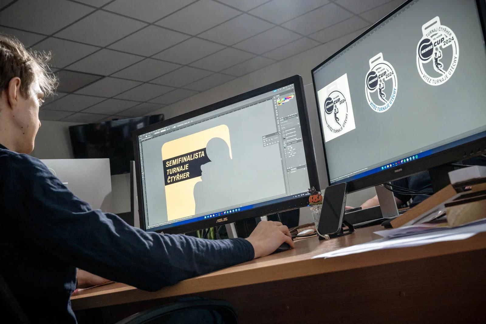 Grafik HOORAY u dvou monitorů připravuje návrh medailí NEMOS CUP 2024 pro turnaj čtyřher