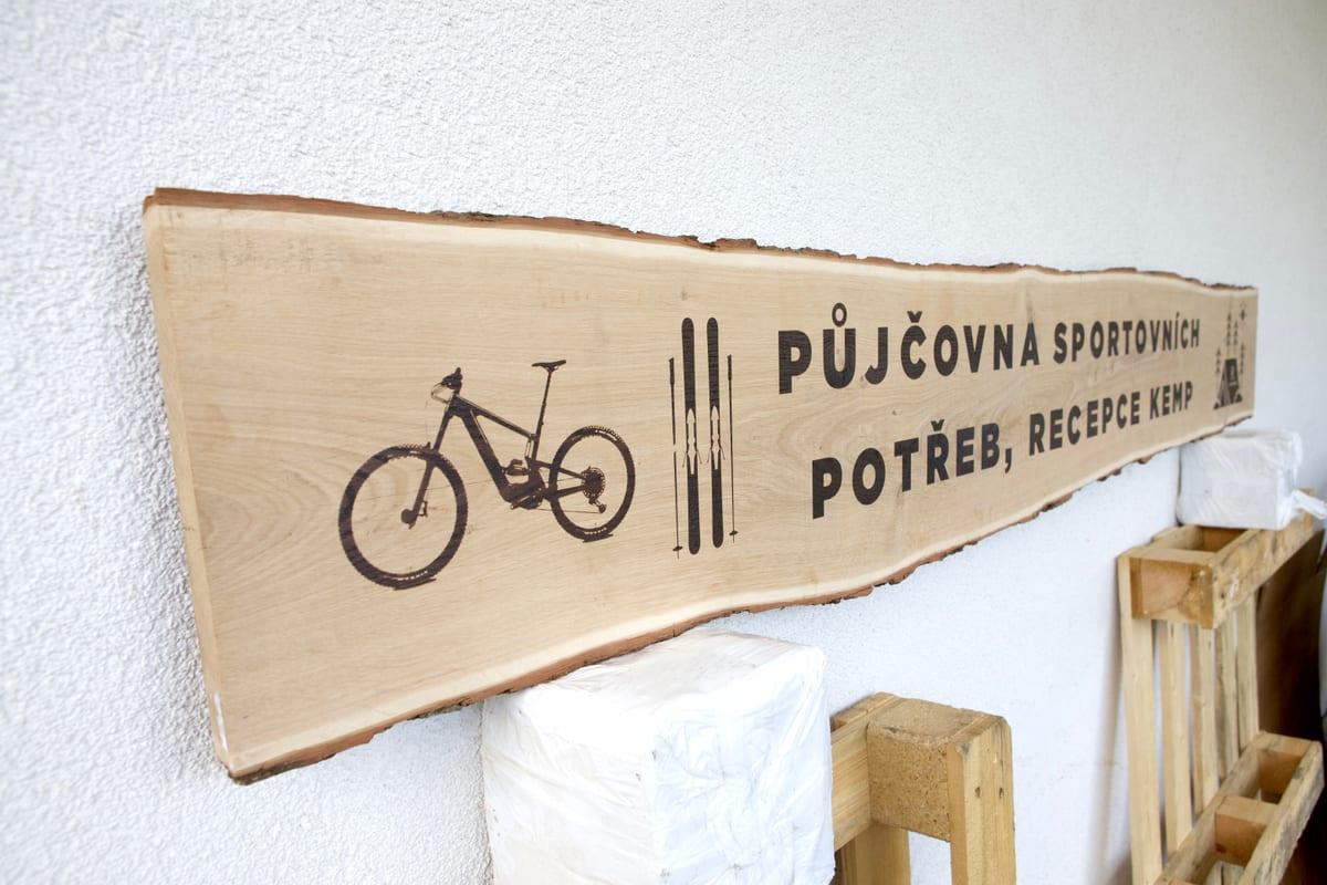 Dřevěná cedule s vypáleným nápisem a piktogramem kola